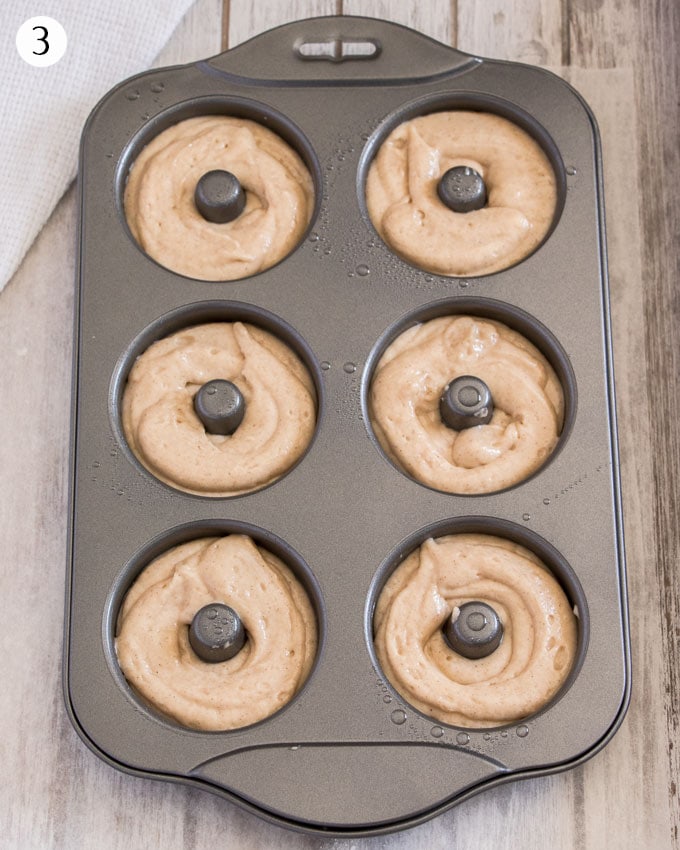 Cake donut batter piped into a donut pan.