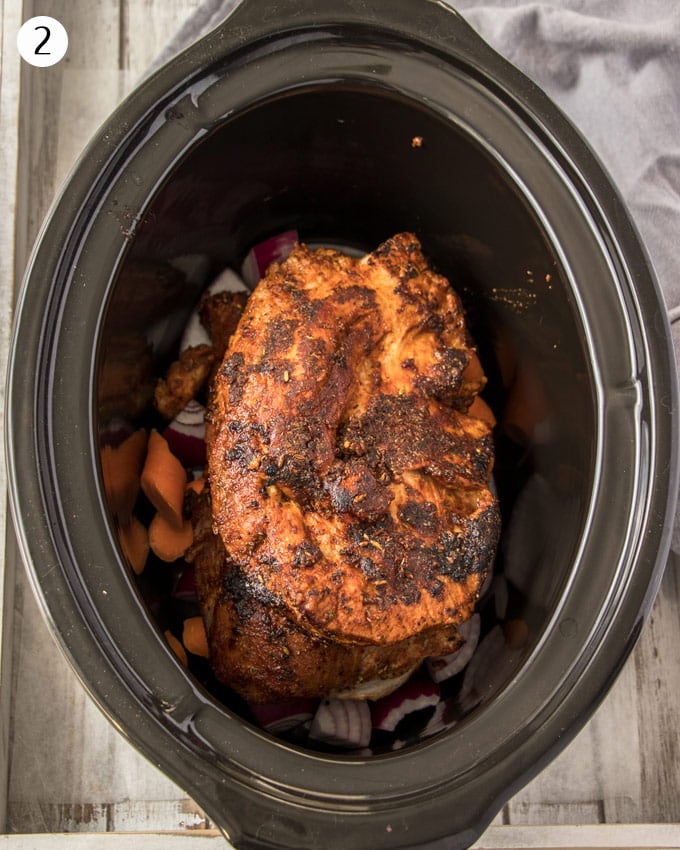 Browned pork in a slow cooker dish ready to slow cook.