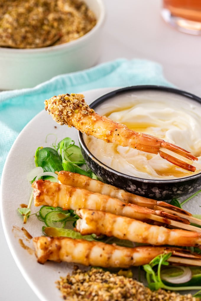 A white plate with prawns, salad and a bowl of yoghurt.