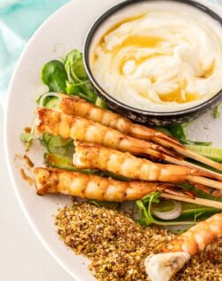 Prawns on a bed of salad with a bowl of yoghurt.