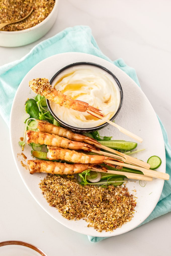 A birdseye view of prawns and salad on a white plate with yoghurt and dukkah.