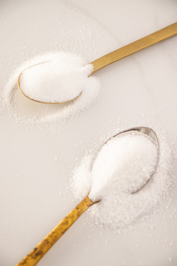 Two spoons showing a close up of 2 types of granulated sugar