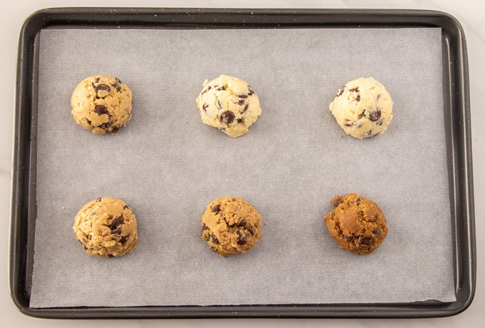 Six mounds of cookie dough on a baking tray