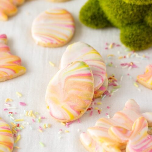 Iced sugar cookies stacked against each other surrounded by sprinkles