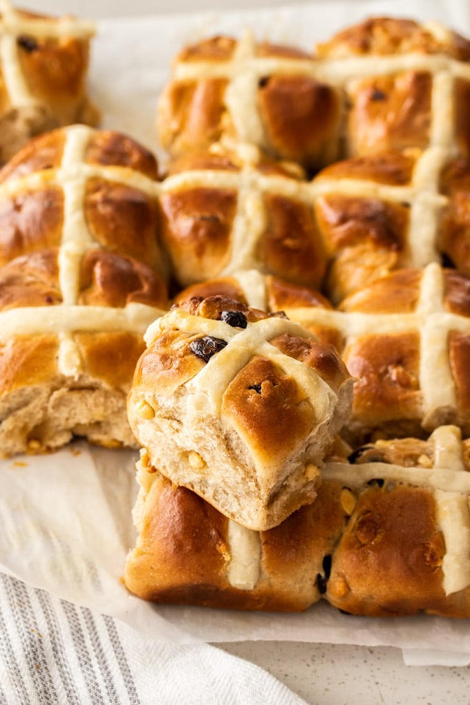 a batch of hot cross buns with one stacked on to of the rest