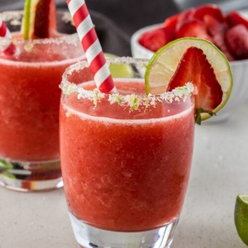 A frozen strawberry daiquiri in a glass with a red straw