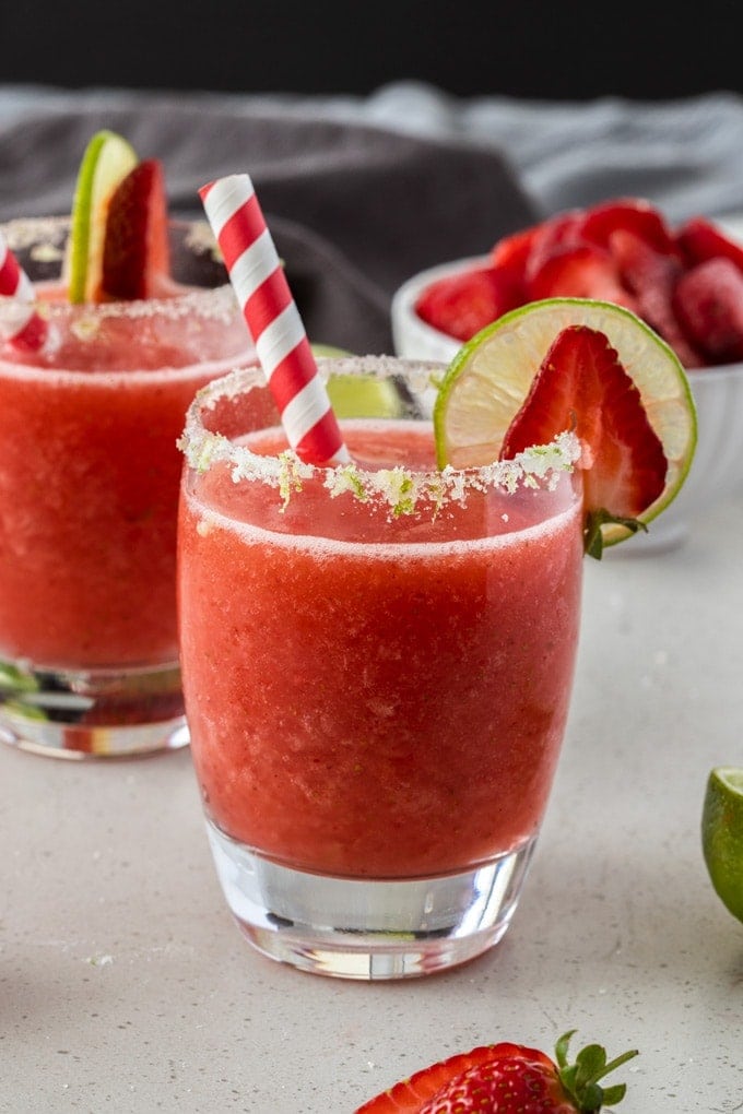 A frozen strawberry daiquiri in a glass with a red paper straw