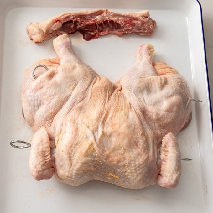 A whole chicken that has been butterflied and is ready to grill