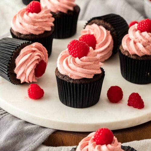 Closeup of a chocolate cupcake with raspberry frosting and topped with a fresh raspberry