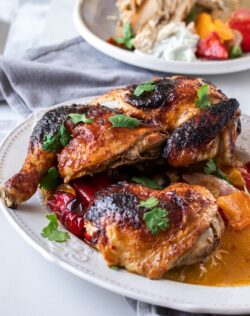 A closeup of roasted harissa chicken on a white plate