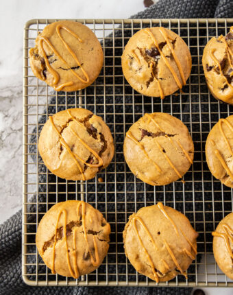 9 muffins on a gold wire cooling rack, drizzled with peanut butter