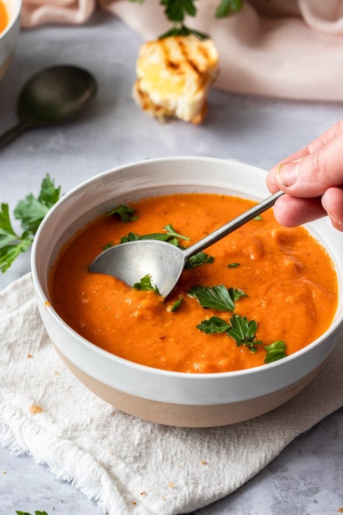 A spoon dipping into a bowl of tomato soup.