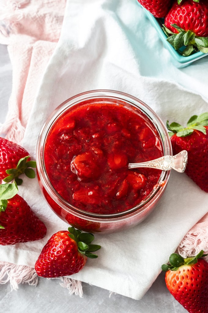 A round glass jar filled with strawberry compote.