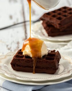 A waffle brownie topped with ice cream having caramel sauce drizzled over.
