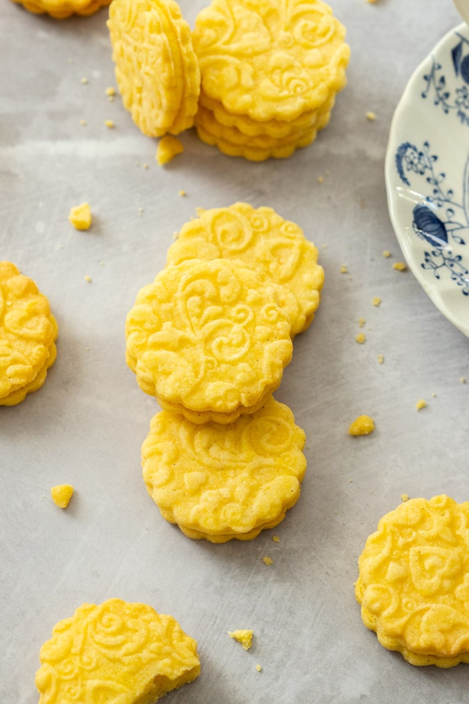 3 stacked custard cream cookies on a grey surface with some others around them