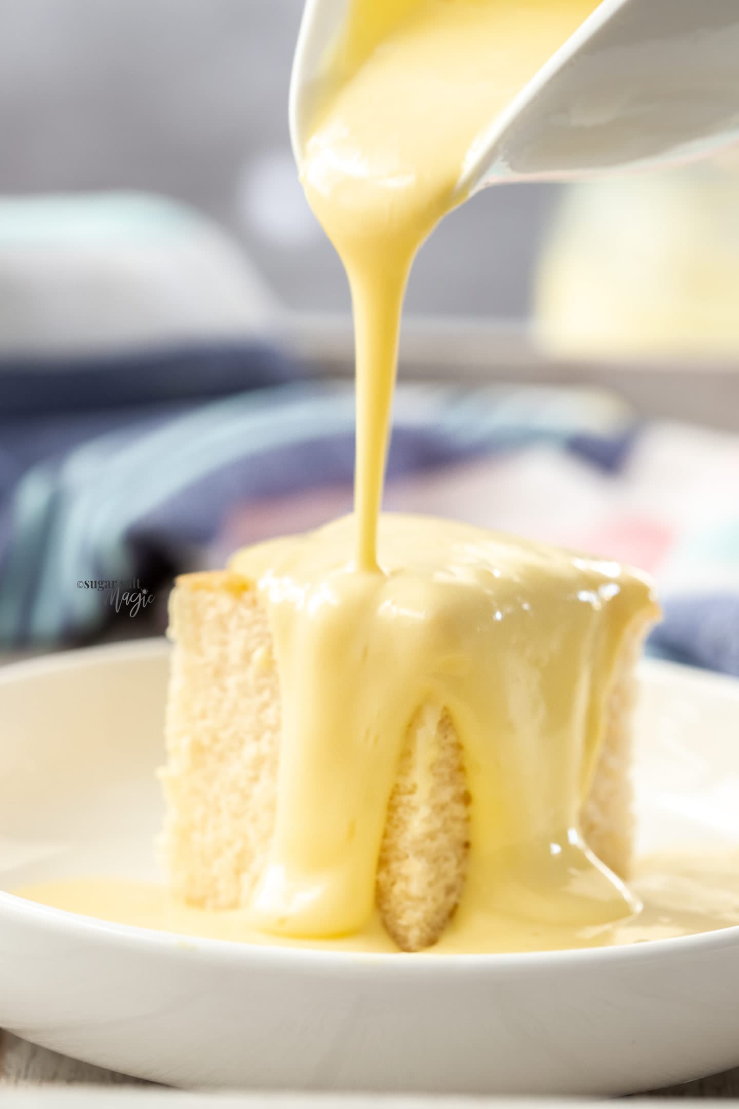 Custard being poured over a piece of cake.