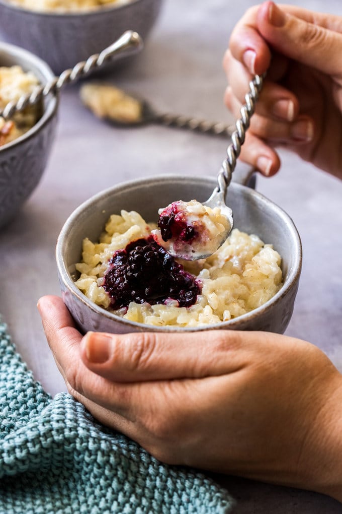 A grey bowl filled with rice pudding and blackberry compote.