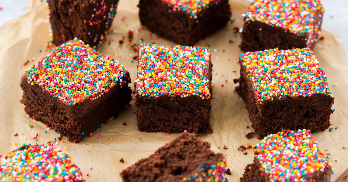 9 square slices of chocolate cake topped with sprinkles on a piece of brown parchment paper