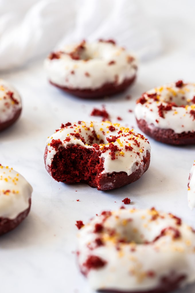 A red velvet donut with a bite taken out of it