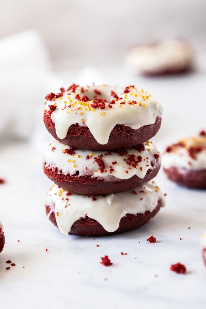 A stack of 3 red velvet donuts with white icing
