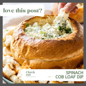 A cob loaf filled with dip sitting on top. Chunks of toasted bread surround it