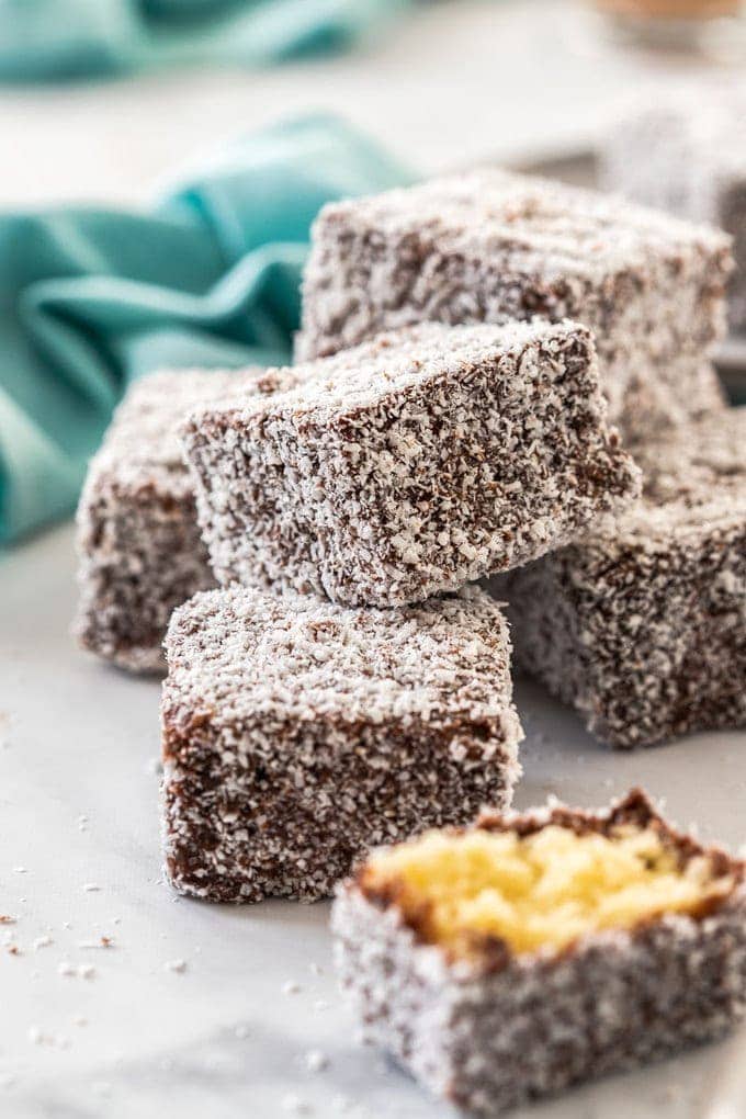A pile of lamingtons with one broken in half and a turquoise napkin in the background.