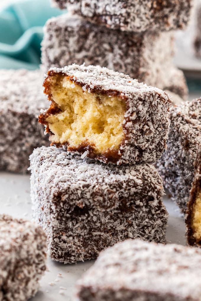Close up of a stack of lamingtons with one broken in half and a turquoise napkin in the background.