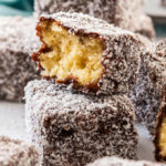 A pile of lamingtons with one broken in half and a turquoise napkin in the background