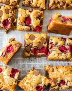 A batch of blondies with chocolate chips and raspberries on a wire rack