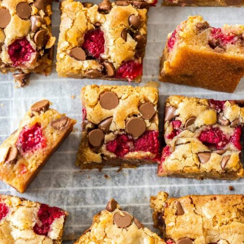 A batch of blondies with chocolate chips and raspberries on a wire rack