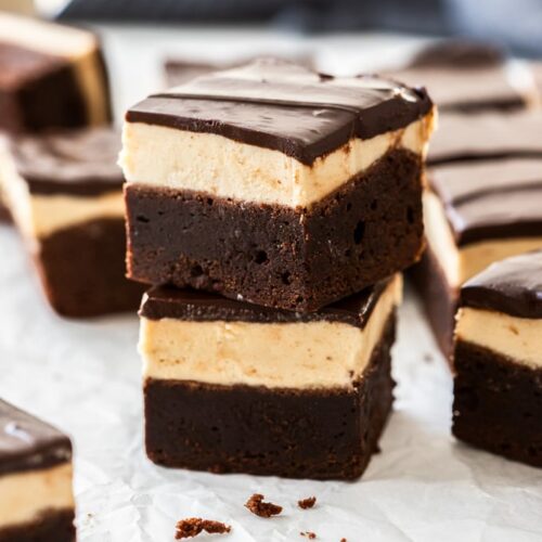 A stack of two baileys brownies on a sheet of baking paper with more brownies around them.