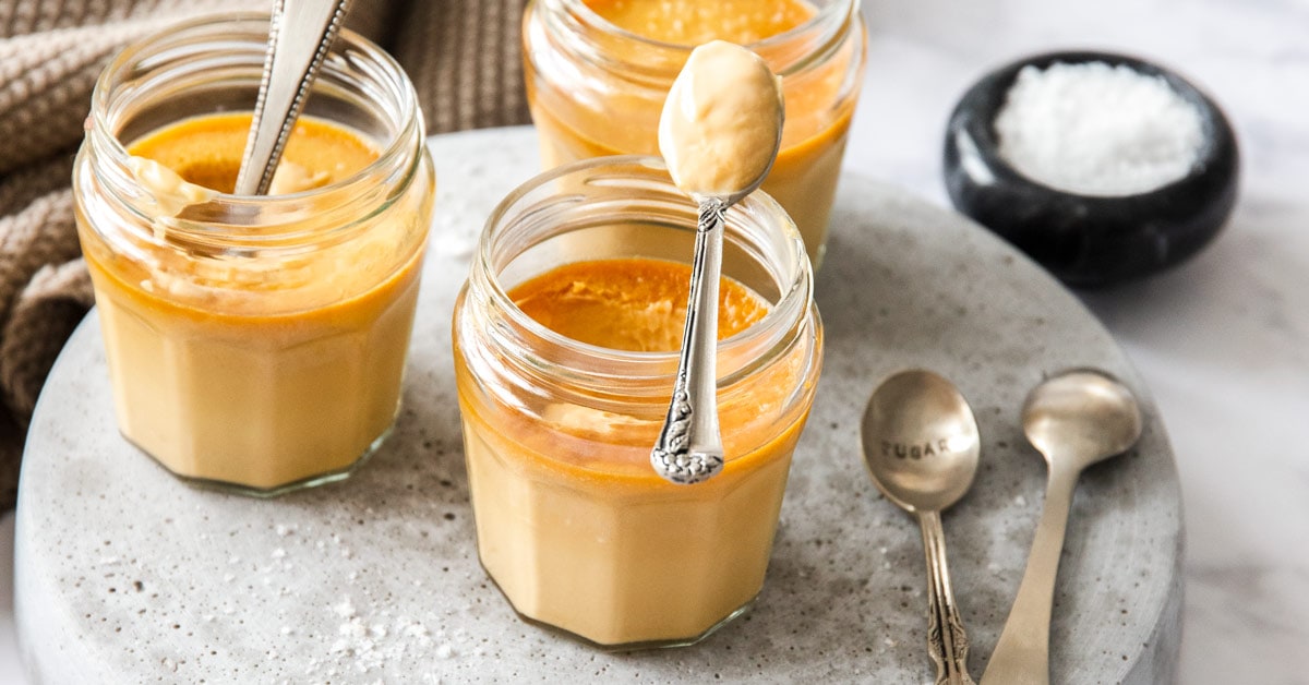 Small glass jars on a grey platter, filled with caramel custard