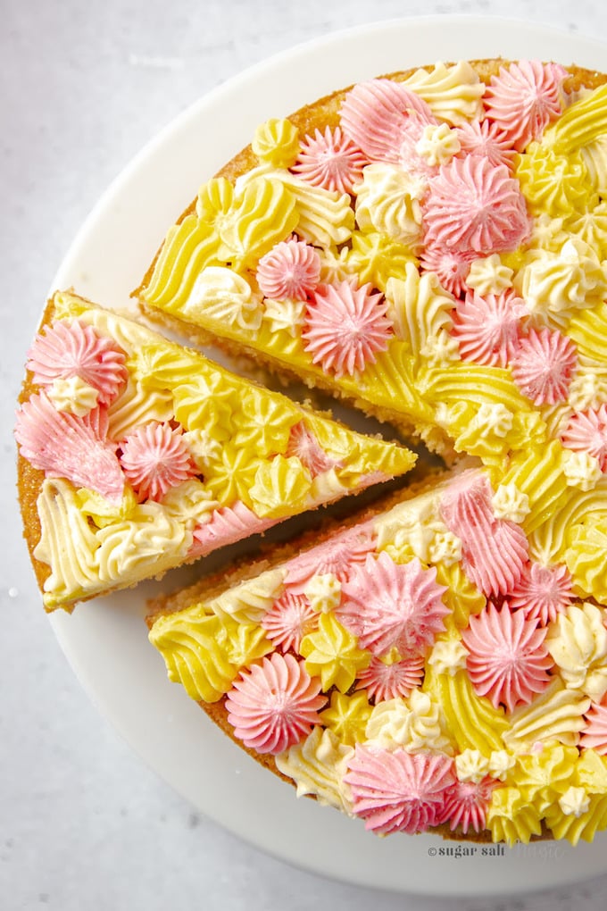 A top down view of a cake with mult coloured frosted stars all over with a slice cut out.