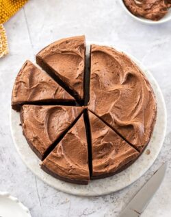A chocolate mud cake cut into slices on a marble cake plate