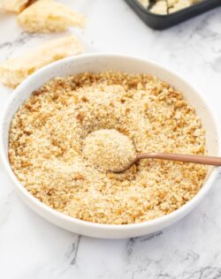 A white bowl filled with breadcrumbs with a spoon in it