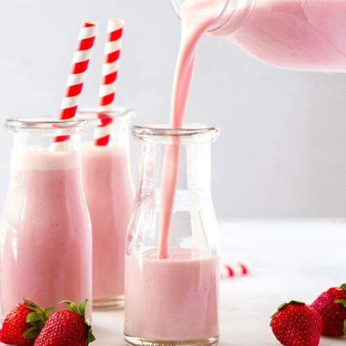 Two bottles of strawberry milk, with more being poured into a third bottle