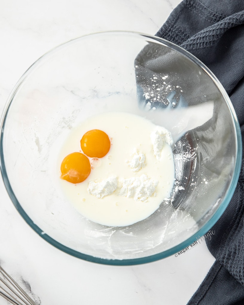 A glass bowl with egg yolks, milk and cornflour.