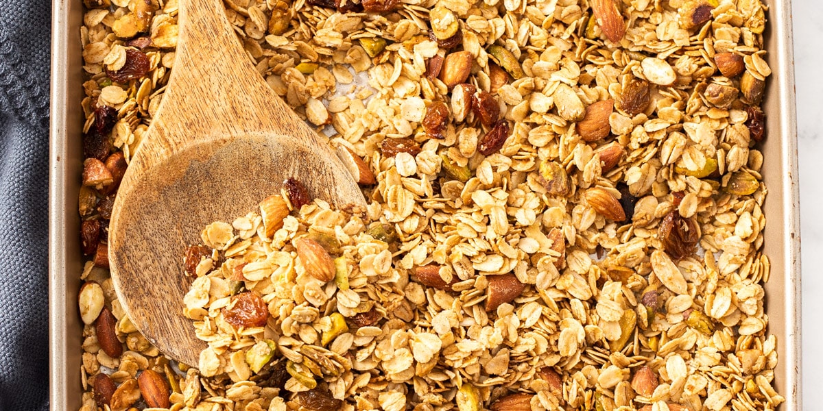 Closeup of a batch of granola with a wooden spoon in it