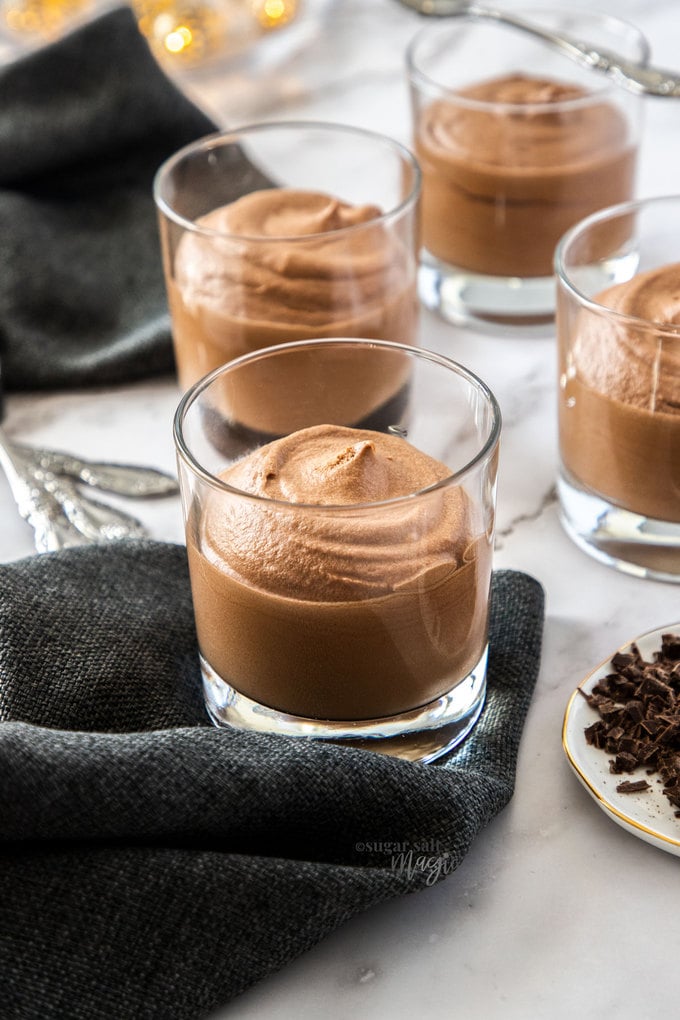 4 glasses filled with mousse sitting on a dark grey napkin