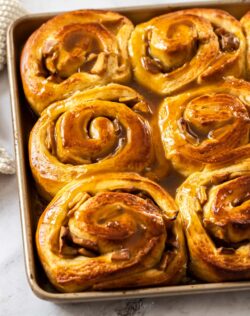 A gold baking tray filled with cinnamon rolls.