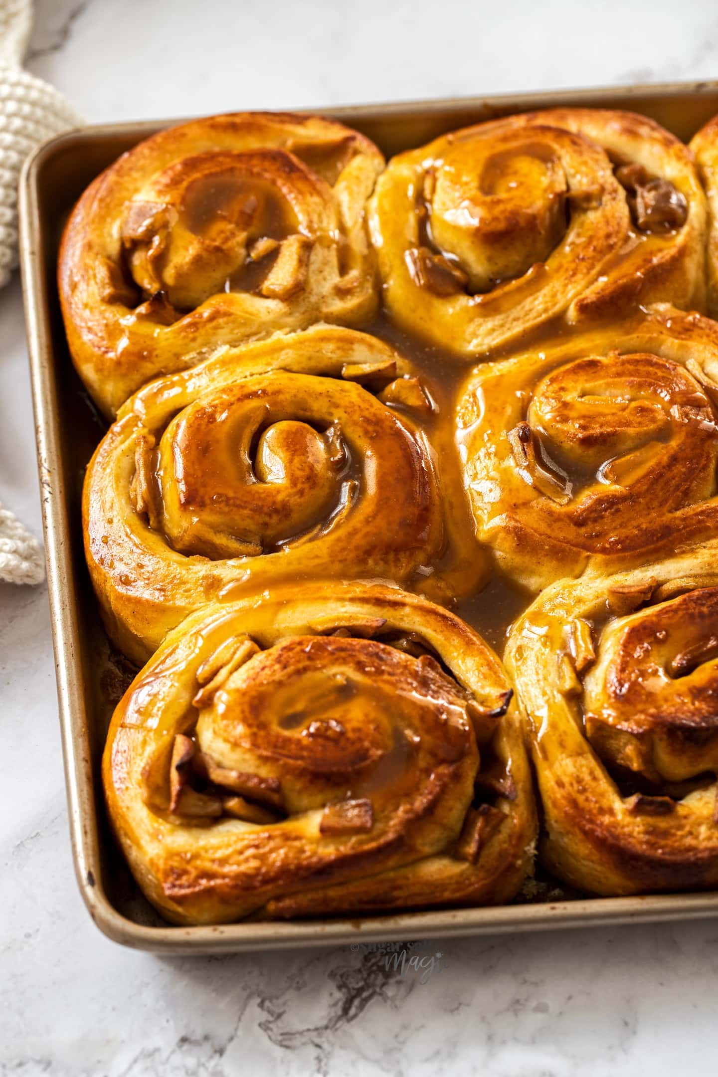 A gold baking tray filled with cinnamon rolls