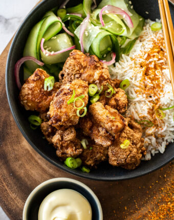 A black bowl filled with rice and fried chicken.
