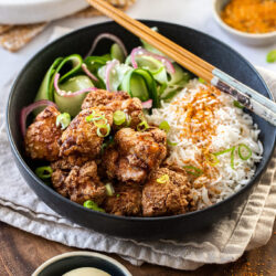 A black bowl filled with rice and fried chicken