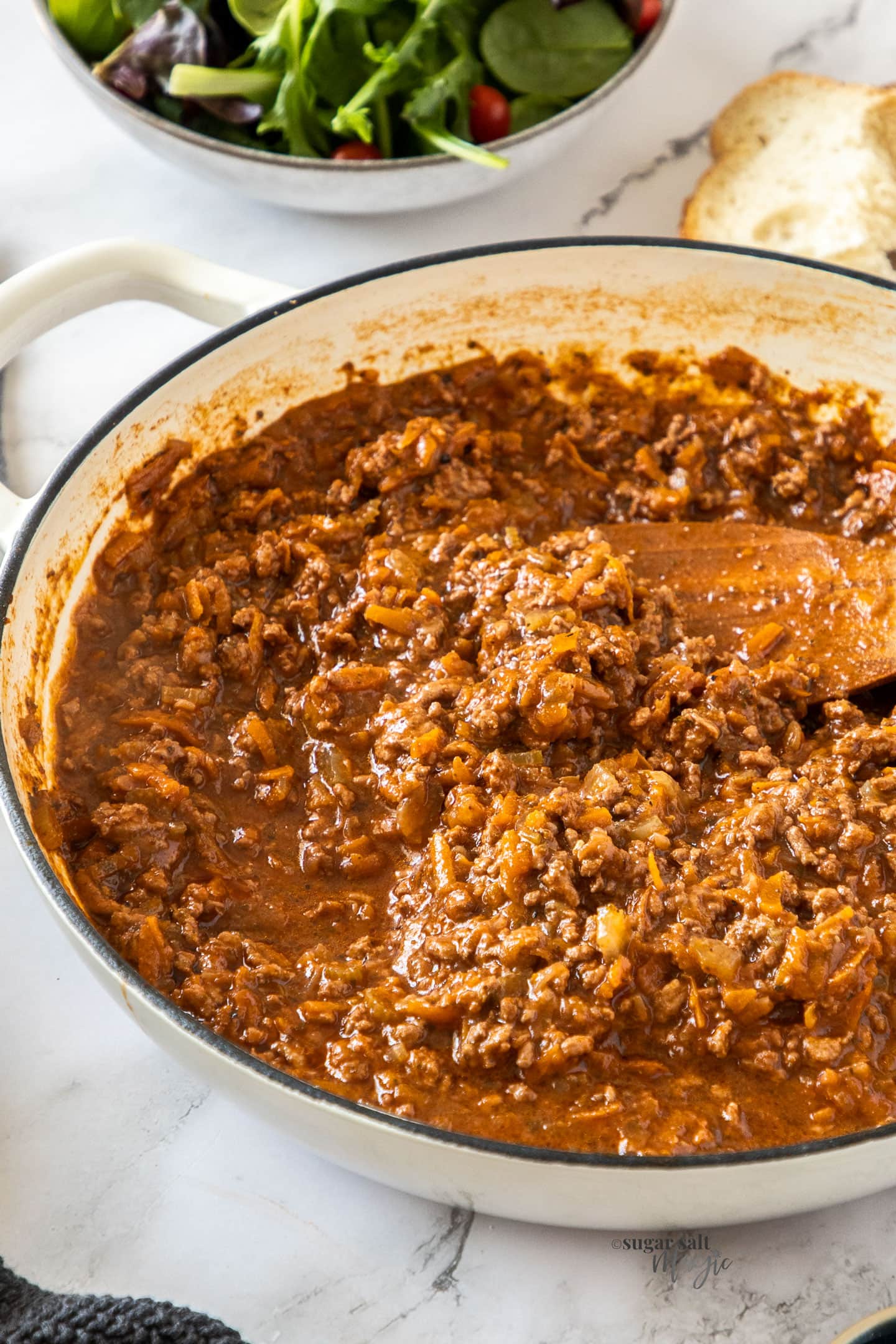 A white casserole dish filled with bolognese sauce.