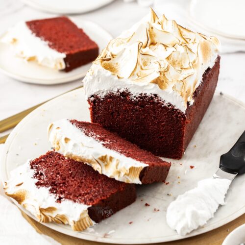 Red velvet cake on a white platter with two slices cut from it.