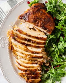A golden turkey breast on a plate, partly sliced, with green salad on the side.