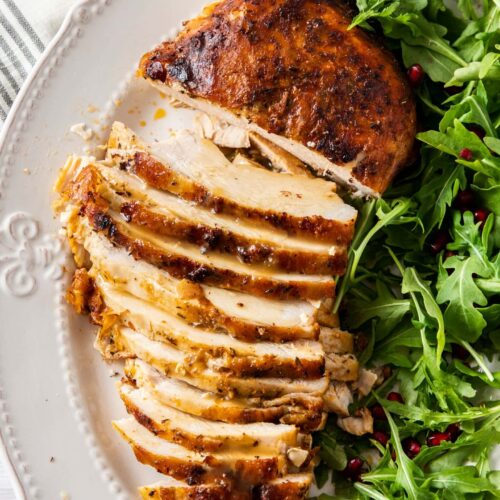 A golden turkey breast on a plate, partly sliced, with green salad on the side.