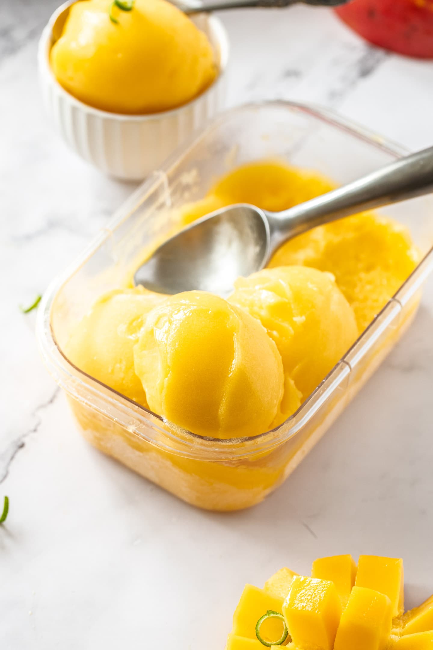 A clear container filled with scoops of mango sorbet.