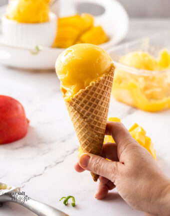 a waffle cone with a scoop of mango sorbet