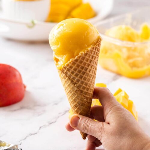 a waffle cone with a scoop of mango sorbet